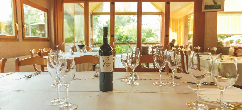Table dressée dans la salle, bouteille de vin et verres